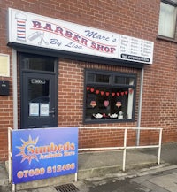 a barber shop with a sign in front of it